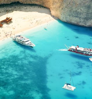 Eine Luftaufnahme eines Schiffswracks am Strand mit türkisfarbenem Wasser.