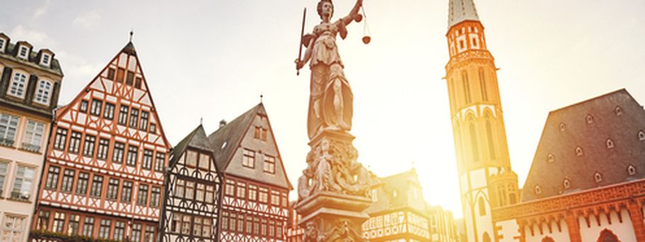 Eine Statue oder ein Denkmal mit einem Gebäude im Hintergrund bei Sonnenuntergang.