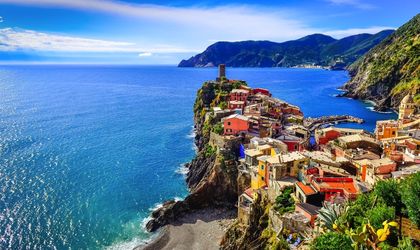Die farbenfrohen Häuser der Cinque Terre, Italien, schmiegen sich an die steilen Klippen über dem Mittelmeer, mit einem Hafen voller Boote im Vordergrund.