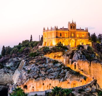 Eine Burg auf einem felsigen Hügel bei Sonnenuntergang.