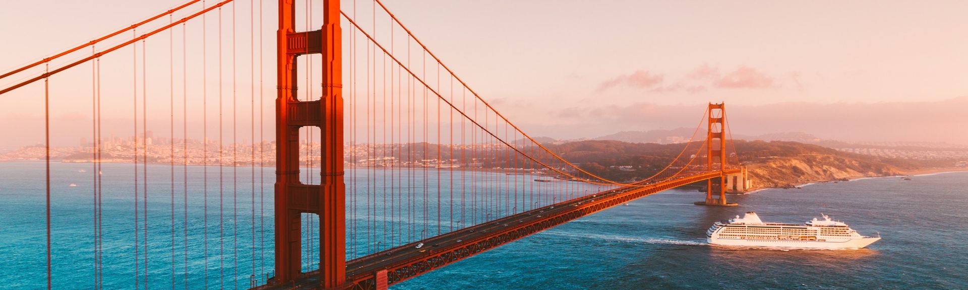 Kreuzfahrtschiff fährt im Sonnenuntergang unter der golden Gate bridge durch
