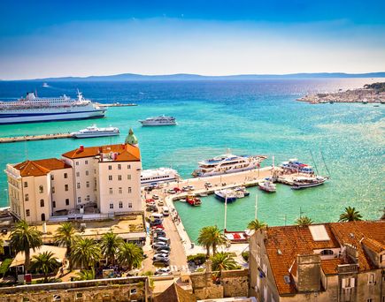 Eine Küstenstadt mit roten Dächern und Blick auf das Meer und Boote.