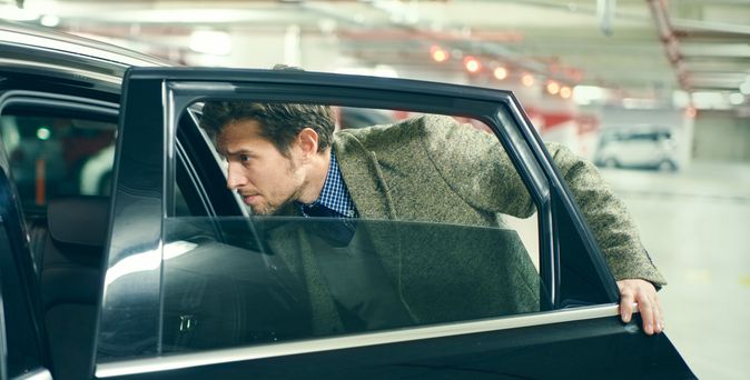 Eine Person sitzt am Steuer eines Autos und blickt zur Seite.