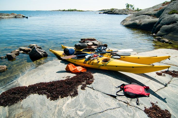 Eine Küstenlandschaft mit Booten am Ufer und gelben Kajaks.