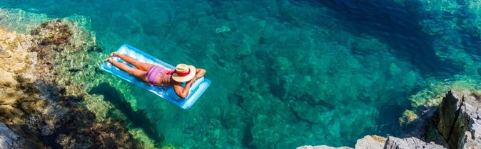 Frau treibt auf einer Luftmatratze im Meer