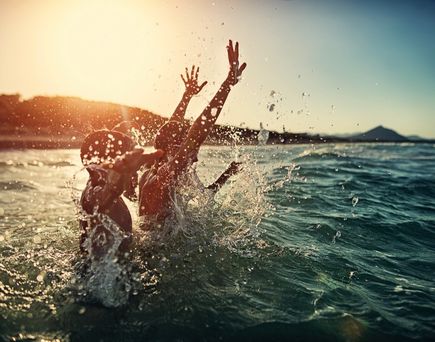 Zwei Kinder spielen im Meer.