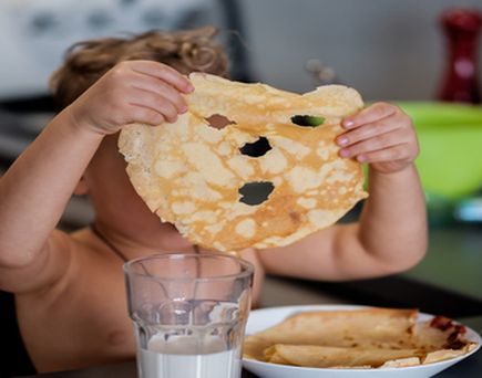 Ein Kind hält ein Stück Pizza oder Gebäck.