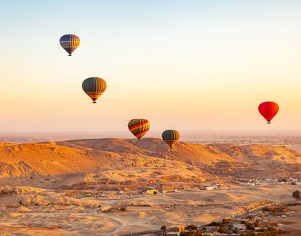 Bunte Heißluftballons schweben im Morgenlicht über die weite Wüstenlandschaft rund um Luxor – ein unvergessliches Abenteuer.