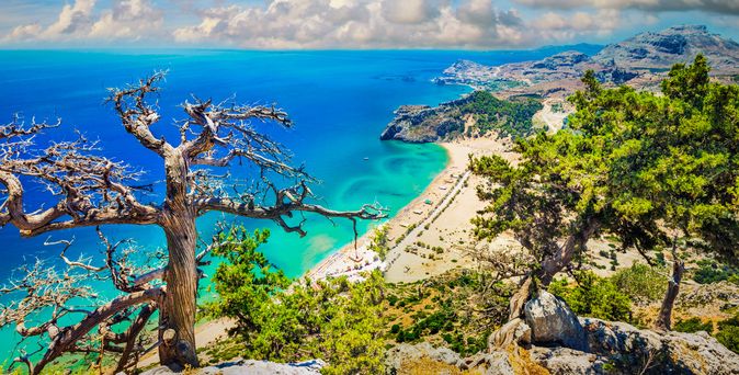 Eine felsige Küstenlandschaft mit Blick auf das Meer und eine Stadt.