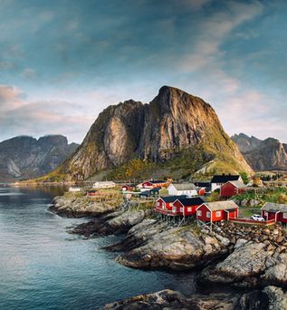 Eine malerische Küstenlandschaft der Lofoten in Norwegen mit einem Dorf und Bergen.