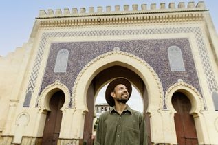 MArokkaner mit Hut vor einem Torbogen