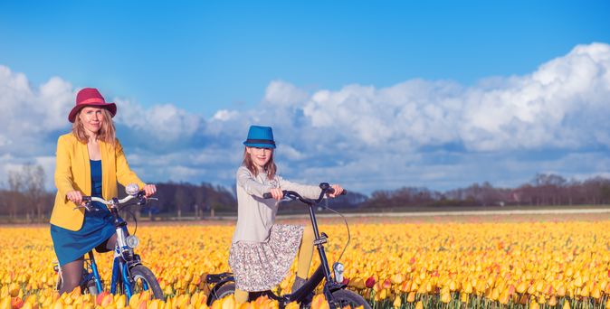 Mutter mit Tochter im Tulpenfeld bei strahlendem Himmel.