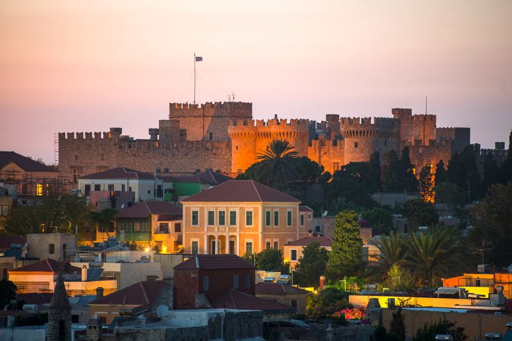 Eine Altstadt auf Rhodos, Griechenland, mit einer Burg bei Sonnenuntergang.