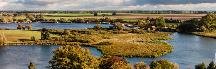 Luftaufnahme der Mecklenburgischen Seenplatte mit Flüssen, Seen, Feldern und kleinen Siedlungen.
