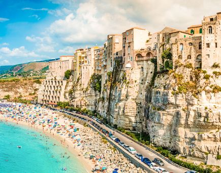 Ein Strand mit türkisfarbenem Wasser und einem felsigen Ufer.