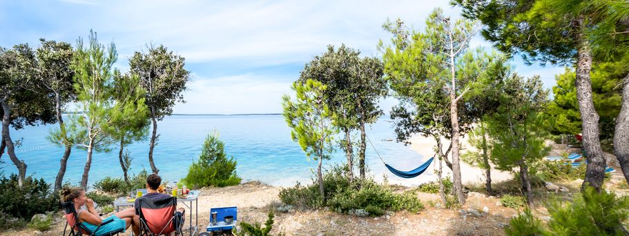 Camping Kroatien Urlaub Personen machen Picknick zwischen Bäumen am Wasser