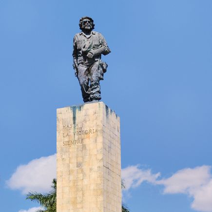 Eine Statue auf einem Sockel vor einem blauen Himmel.