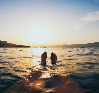 Zwei Personen schwimmen im Meer bei Sonnenuntergang.