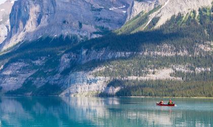 Rotes Boot auf dem Lake Moraine mit schneebedeckten Bergen im Hintergrund