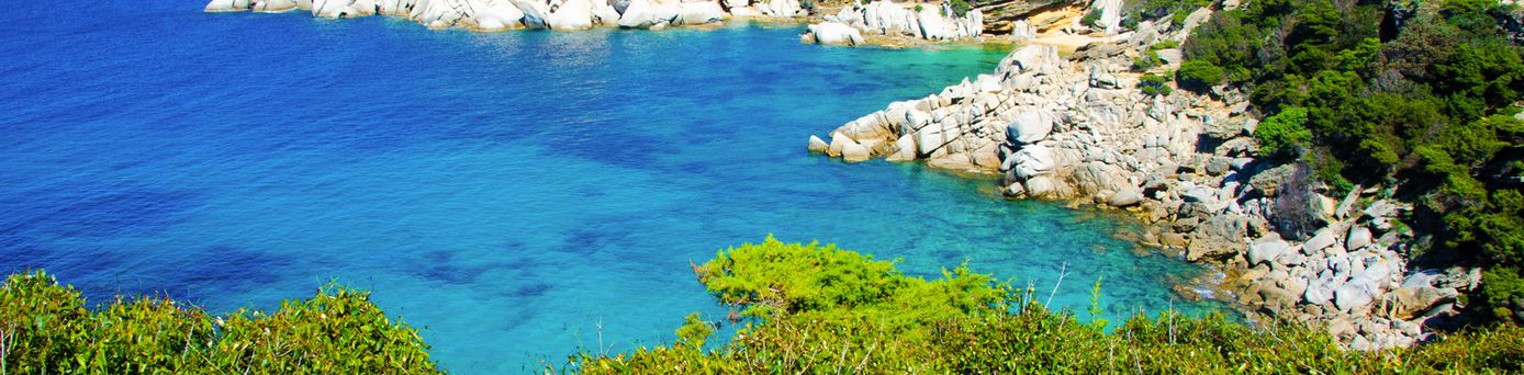 Eine atemberaubende Küstenlandschaft von Capo Testa auf Sardinien, Italien, mit markanten Felsformationen und dem türkisblauen Meer, das sich bis zum Horizont erstreckt.