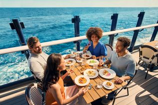 Mehrere Menschen sitzen beim Essen an Deck der Mein Schiff