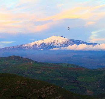 Eine Berglandschaft mit Wolken und einem Tal bei Sonnenuntergang.