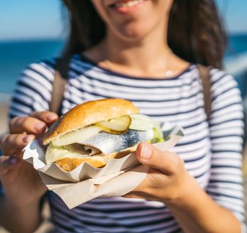 Eine Frau halt ein gut gefülltes Fischbrötchen in der Hand.