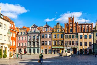 Marktplatz von Posen. Viele schmale, alte und bunte Häuser sind zu sehen. Strahlend blauer Himmel.