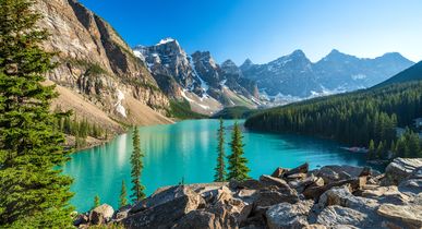 Aussagekräftige Berglandschaft, inmitten ein türkisblauer See und rundherum einige Bäume.