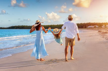 Paar läuft mit KInd am Strand