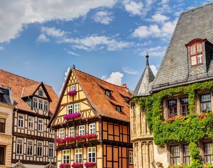  Die historische Stadt Quedlinburg in Deutschland mit ihren Fachwerkhäusern und dem Schloss im Hintergrund unter einem klaren blauen Himmel.