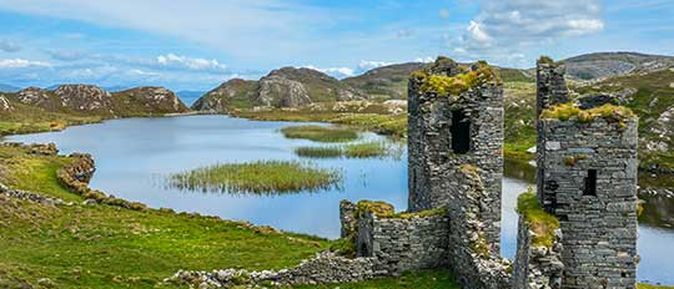Eine Landschaft mit einem See oder Fjord und einer Burgruine.