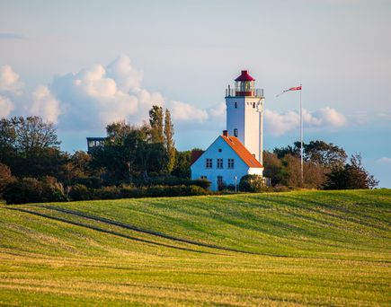 kleiner Turm im Hintergrund, im Vordergrund grüne Wiese. Schöner blauer Himmel. Ort Gedser in Dänemark