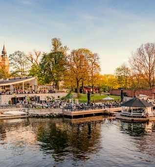 Eine Stadtansicht mit Gebäuden und einem Fluss, umgeben von Herbstbäumen.