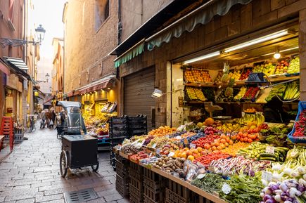 Eine schmale Gasse mit Obstständen bei Sonnenaufgang.