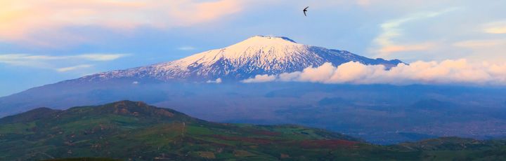 Eine Berglandschaft mit Wolken und einem Tal bei Sonnenuntergang.