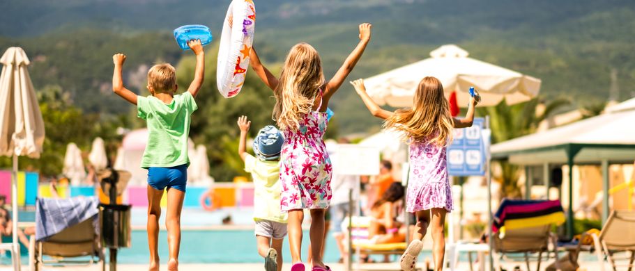Kinder laufen mit Schwimmutensilien richtung pool