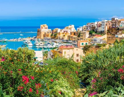 Eine Küstenstadt mit roten Dächern und Blick auf das Meer.