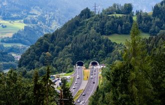 Panoramablick auf eine grüne Berglandschaft mit Wäldern und einem Tal.