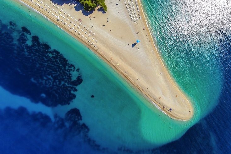 Eine Luftaufnahme einer Sandbank, die ins türkisfarbene Meer ragt.