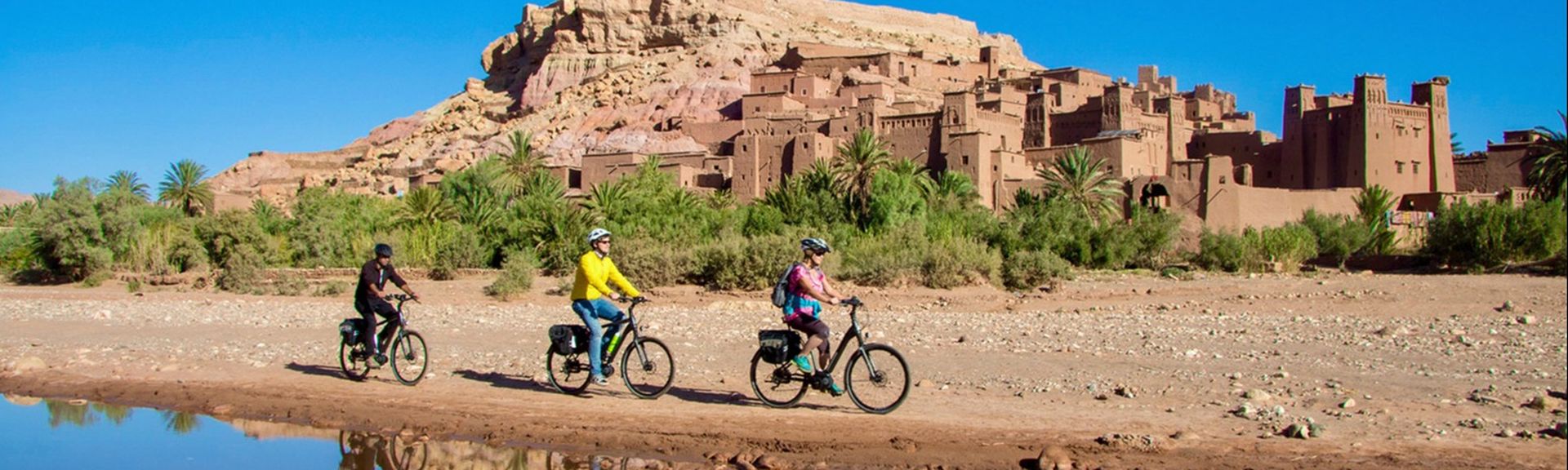 Drei Personen fahren Fahrrad durch eine orientalische Landschaft
