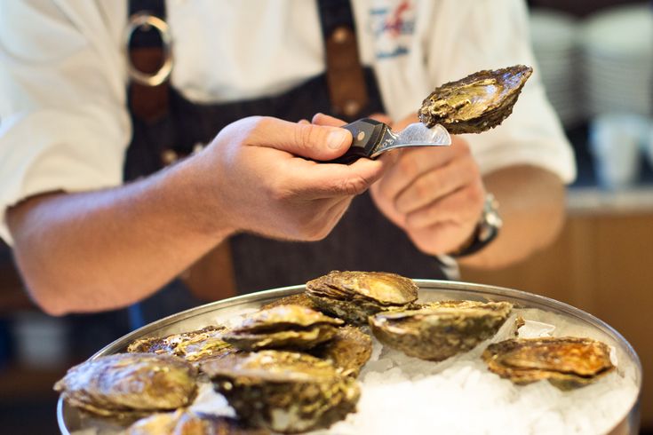 Person isst frische Austern und Meeresfrüchte an einem Tisch in einem schwedischen Restaurant.