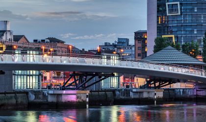 Die Fußgänger- und Fahrradbrücke Lagan Weir in Belfast, Nordirland, bei Tageslicht, mit Blick auf die Brückenstruktur und das umliegende Stadtgebiet.