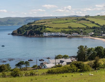 Der Strand von Cushendun und die umliegende Landschaft und die Grashügel an einem warmen, sonnigen Tag in der Grafschaft Antrim, Nordirland 
