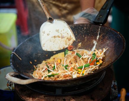 Ein appetitlich angerichteter Teller Pad Thai, ein traditionelles thailändisches Nudelgericht mit Garnelen, Erdnüssen und Limettenspalten.