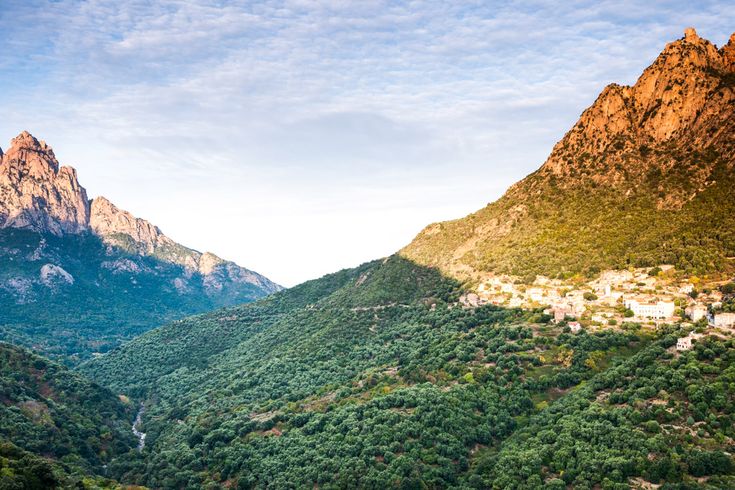 Eine weite Berglandschaft mit einem See oder Fjord, der sich in den Bergen spiegelt, unter einem klaren blauen Himmel.