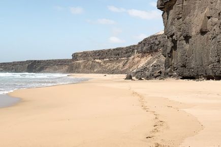 Dunkle Felsvorsprünge am weitläufigen Playa de Corralejo auf Fuerteventura.