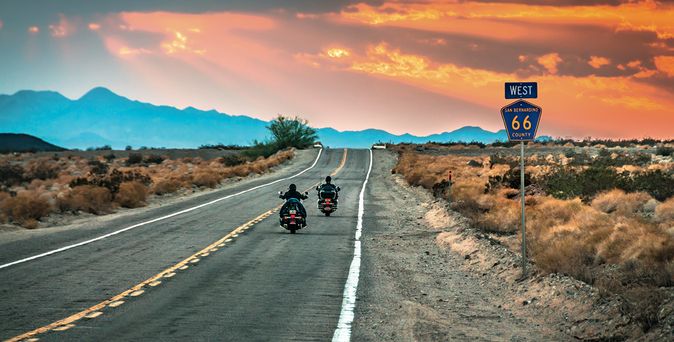 Straße Route 66 mir 2 Motorradfahrern und Bergen am Horizont