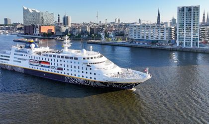 Ein Kreuzfahrtschiff fährt auf einem Fluss in Hamburg, mit der Elbphilharmonie im Hintergrund.