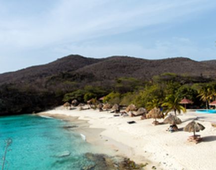 Ein felsiger Strand mit türkisfarbenem Wasser und einem blauen Himmel.